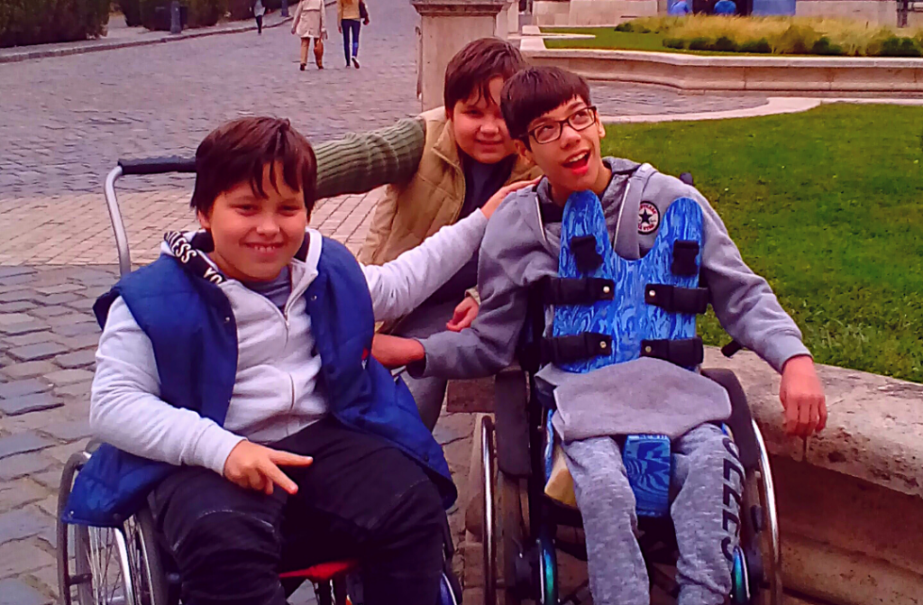 The students of the School of Tomorrow (three preteen boys, two of them in wheelchairs) hugging and smiling on a school trip.